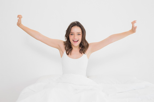 Smiling woman stretching her arms in bed - Foto, Bild