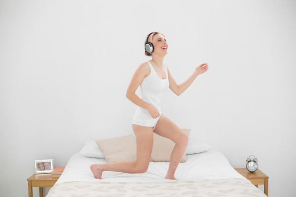 Laughing woman playing air guitar while listening to music - Foto, Bild