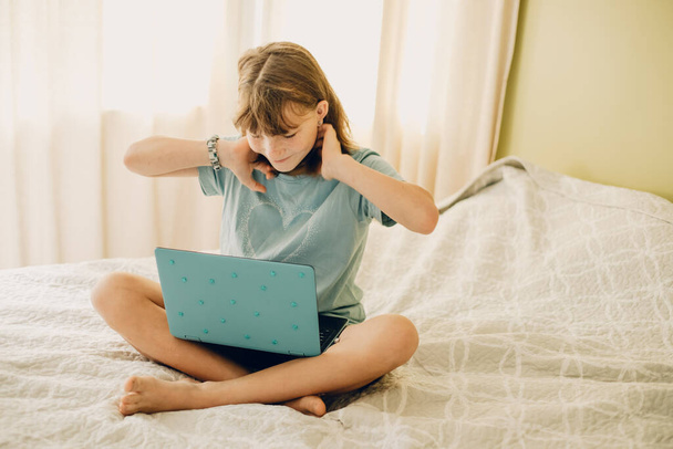 indoor casual portrait of child girl with laptop lying on bed at home - 写真・画像