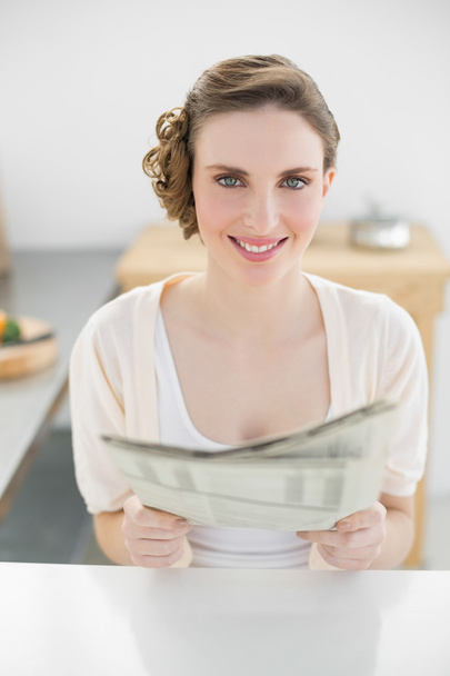 Gorgeous calm woman holding newspaper sitting in her kitchen - Foto, imagen