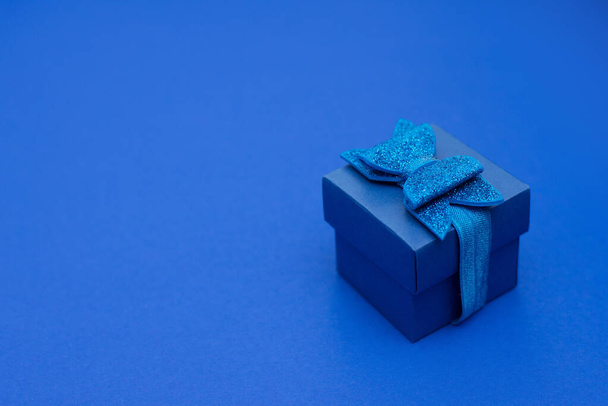 Caja de regalo azul con cinta, lazo sobre fondo azul clásico, espacio para copiar
 - Foto, Imagen