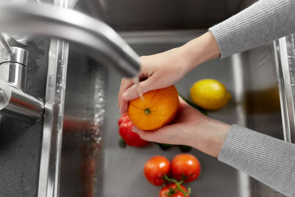 woman washing fruits and vegetables in kitchen - Foto, Imagen