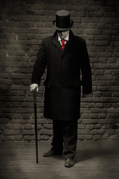 man in de zwarte jas, hoge hoed en in een rode stropdas - Foto, afbeelding