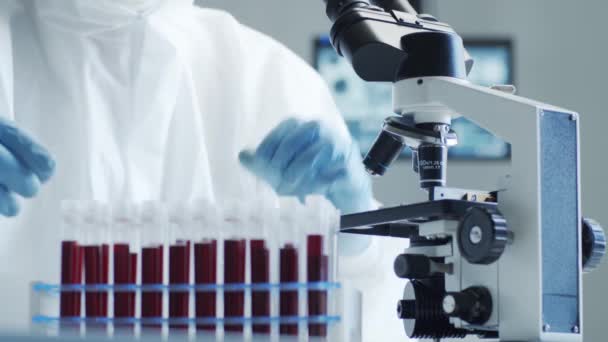 Wissenschaftler in Schutzanzügen und Masken arbeiten im Forschungslabor mit Laborausrüstung: Mikroskope, Reagenzgläser. Coronavirus 2019-ncov hazard, pharmazeutische Entdeckung, Bakteriologie und Virologie - Filmmaterial, Video