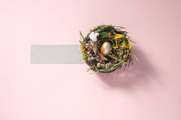 Easter still life. Chicken egg in a nest on a pale pink surface. Holiday concept. Copy space. Postcard design concept. Place under the text. - Fotografie, Obrázek