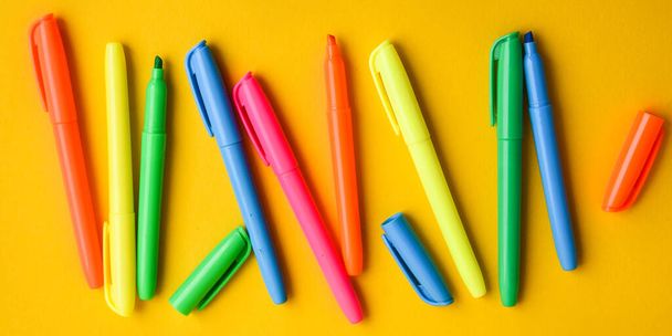 Felt-tip pens on a yellow background with copy space, set of new bright plastic opened colored felt pens near the caps . concept of office supplies - Foto, Imagen
