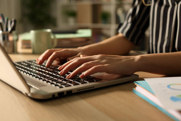 Закрыть руки предпринимателя, работающего на ноутбуке, сидящего за столом ночью в домашнем офисе
 - Фото, изображение