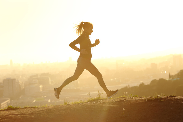 Profil běžecké siluety běžící při západu slunce venku na okraji města - Fotografie, Obrázek