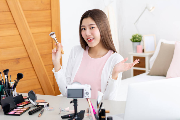 jong aantrekkelijk aziatische vrouw schoonheid vlogger houden make-up borstel doen live streaming in de voorkant van de camera - Foto, afbeelding