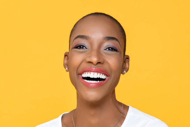 Close up portrait of friendly happy African American woman smiling on isolated colorful yellow background - Photo, Image