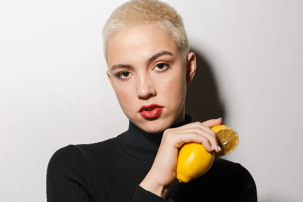 Portrait of an attractive young blonde short haired woman posing with lemons isolated over white background - Foto, Bild
