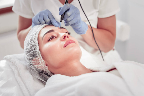 Young woman enjoying facial treatment visiting cosmetologist - Zdjęcie, obraz