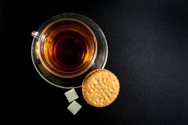 tasse de thé avec sucre et biscuits sur un fond sombre
 - Photo, image