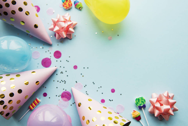 Happy birthday or party background.  Flat Lay wtih birthday hats, confetti and ribbons on blue background. Top View.  Copy space. - Fotó, kép