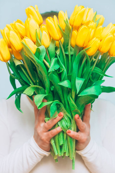 Tulips. Bright bouquet of yellow tulips in female hands. Spring flowers. Flowers tulips for mother, wife, girlfriend etc, conceptual greeting photo - Foto, Imagem