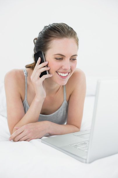 Smiling casual woman using cellphone and laptop - Foto, Imagem