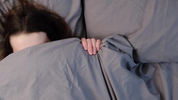 Top view of cheerful young woman hides under soft grey blanket, has fun in bed, look at camera, rejoices good morning, rests in bed. View from above. Copy space. People and sleeping concept. - Séquence, vidéo