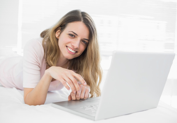 Smiling young woman lying in front of her laptop - Foto, imagen