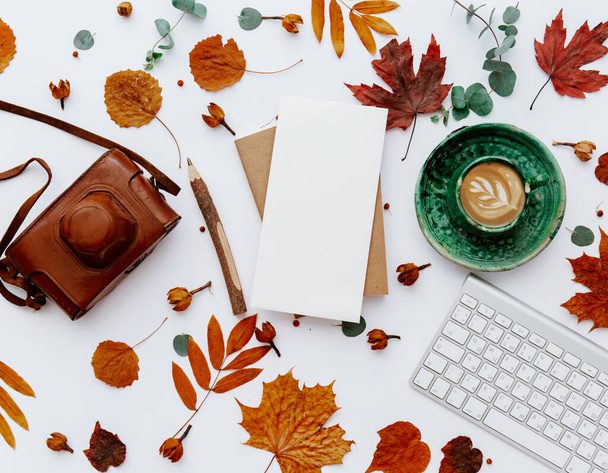 Top view of coffee cup, keyboard and blank paper with autumn leaves. Home workspace, fall scene  - Foto, Imagen