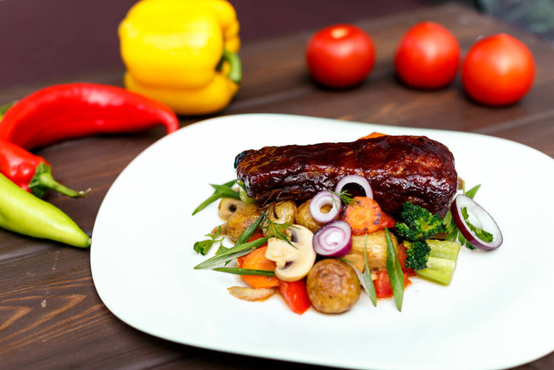 Telecí steak s mladými bramborami a šťavnatou zeleninou na dřevěném pozadí - Fotografie, Obrázek
