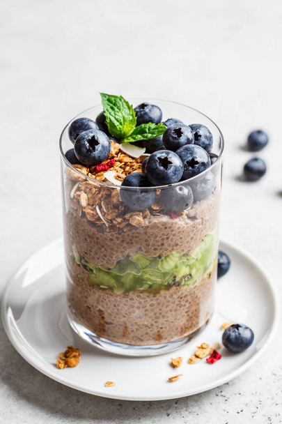 Chocolate chia pudding with fruits, granola and berries in a glass. - Foto, Bild