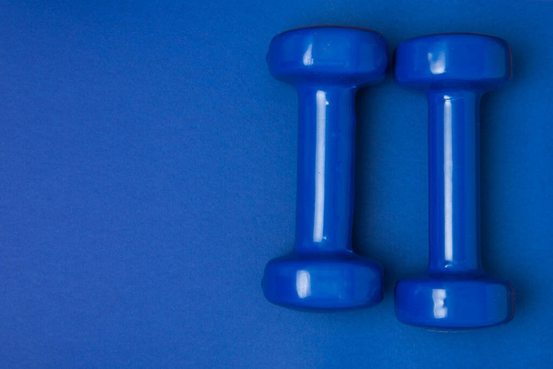 Two blue of dumbbells Isolated on blue background. - Foto, afbeelding