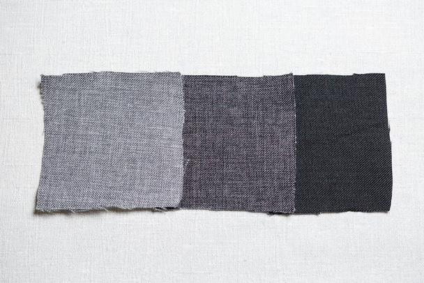 square pieces of multi-colored fabric laid out on a gray background - Photo, Image