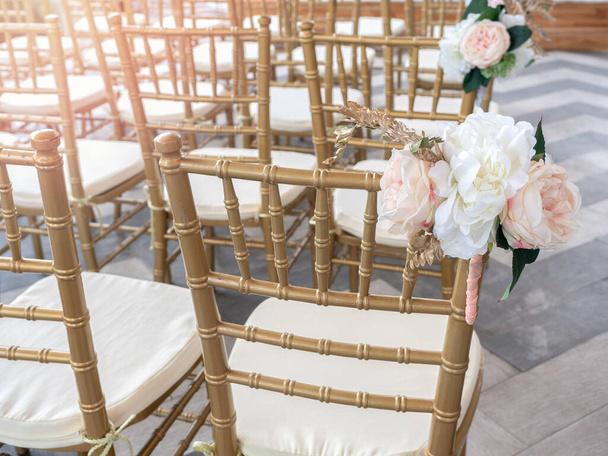 Chaises de mariage décorer avec de belles fleurs pour la cérémonie de mariage. Mariage organisé avec des chaises dorées
. - Photo, image