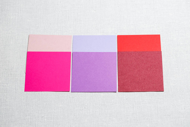 квадратні шматочки різнокольорової тканини, викладені на сірому фоні
 - Фото, зображення
