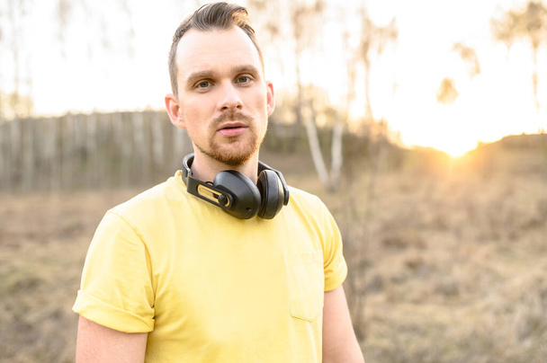 Athletic guy with headphones outdoors at sunset - Valokuva, kuva