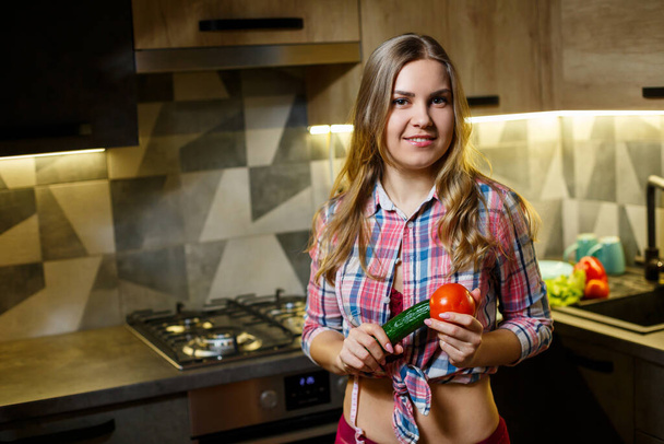 Girl with beautiful figure holds vegetables - 写真・画像