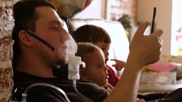 Ojciec z inhalatorem odpoczywający w domu z dziećmi - Materiał filmowy, wideo