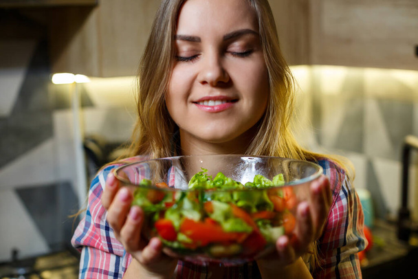 girl fitness trainer vegetarian nutritionist prepare fresh vegetable salad in the kitchen. Watching her figure - Фото, изображение