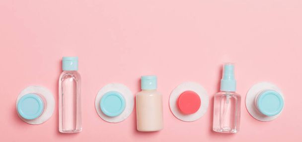 Top view of means for face care: bottles and jars of tonic, micellar cleansing water, cream, cotton pads on pinkbackground. Bodycare concept with empty cpace for your ideas. - Photo, Image