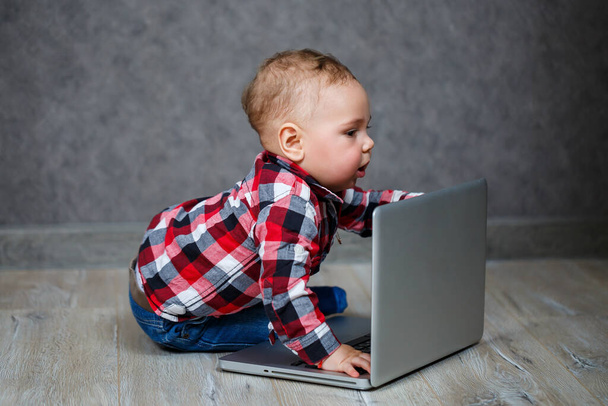 Little kid in shirt plays with laptop - Foto, imagen