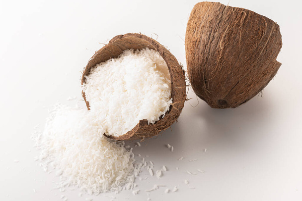 coconut flakes lies in a coconut shell, cut into two halves - Фото, зображення