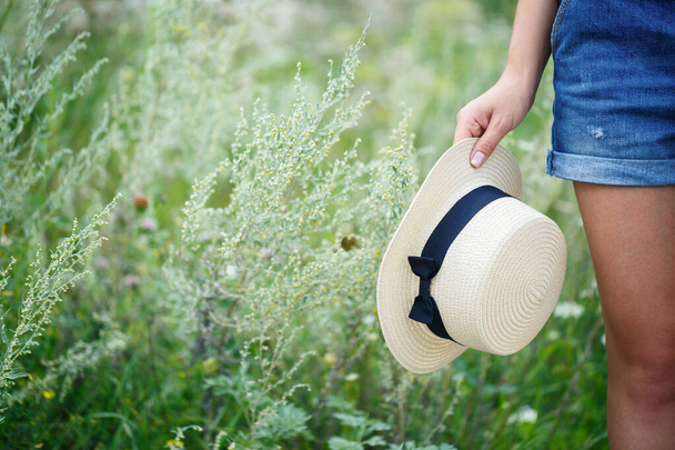 молодая красивая девушка в джинсовом комбинезоне и легкой шляпе прогуливаясь по парку
 - Фото, изображение
