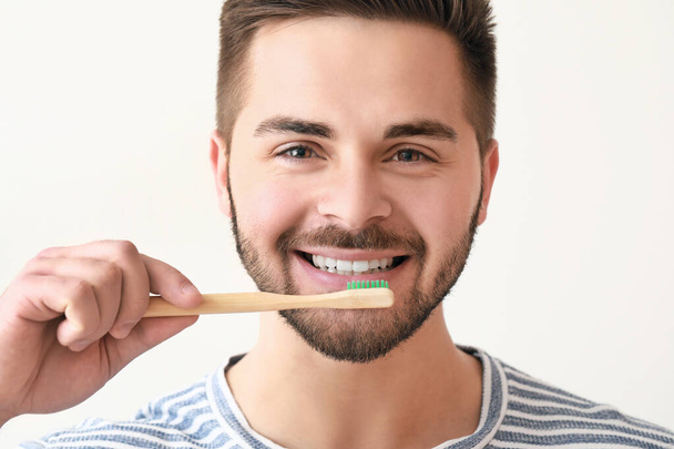 Jeune homme souriant avec une brosse à dents sur fond blanc - Photo, image