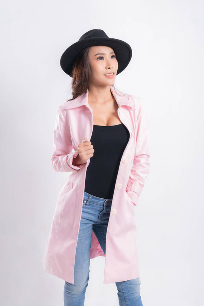Young elegant woman in trendy pink coat wearing a black hat, at fashion studio portrait shot isolated on white background. - Фото, зображення