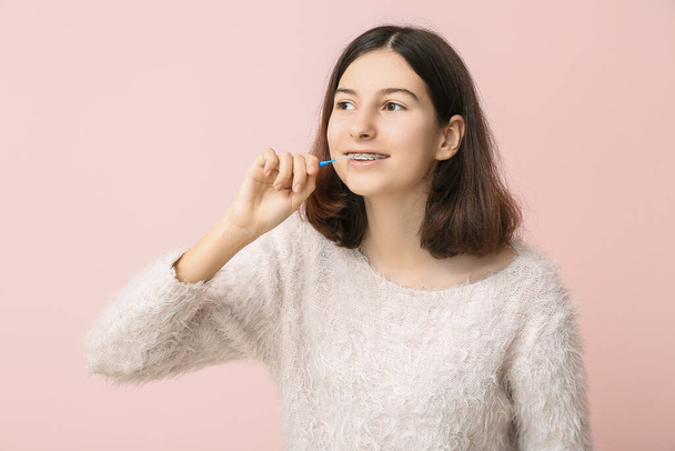 tiener meisje met gebit beugels en borstel op kleur achtergrond - Foto, afbeelding