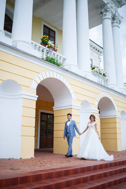 Молодой стильный парень в костюме жениха и невеста красивая девушка в белом платье с железнодорожной прогулкой в парке в день их свадьбы
 - Фото, изображение