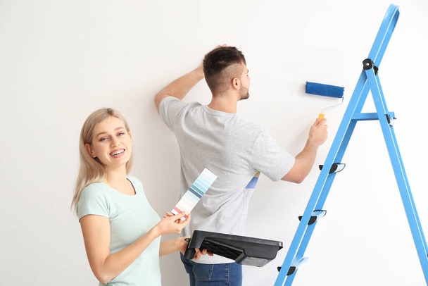 Young couple choosing color of wall on white background - Фото, зображення