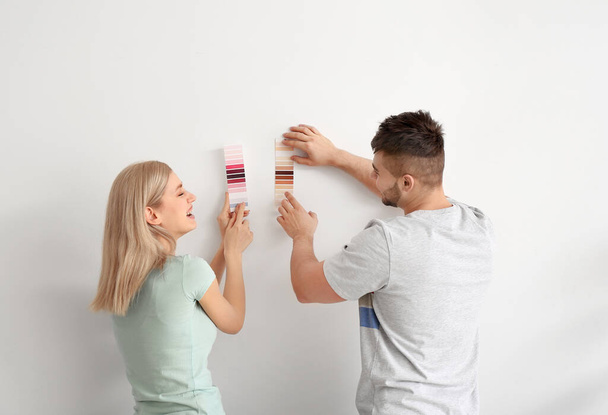 Young couple choosing color of wall on white background - Foto, imagen