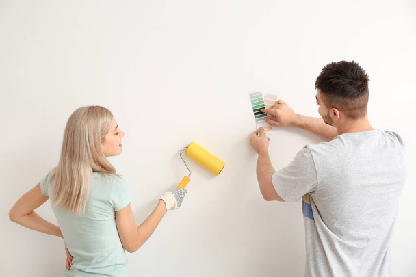 Young couple choosing color of wall on white background - 写真・画像