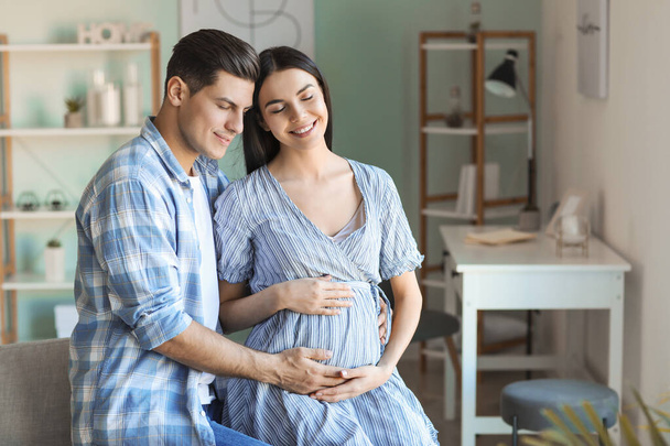 Portrait of happy pregnant couple at home - Foto, afbeelding