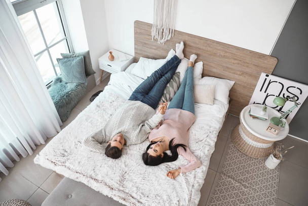 Happy young couple lying on bed at home - Photo, image