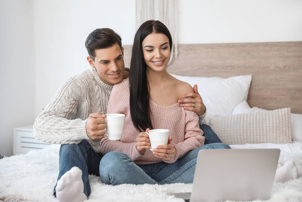 Happy young couple with laptop in bedroom - Photo, Image