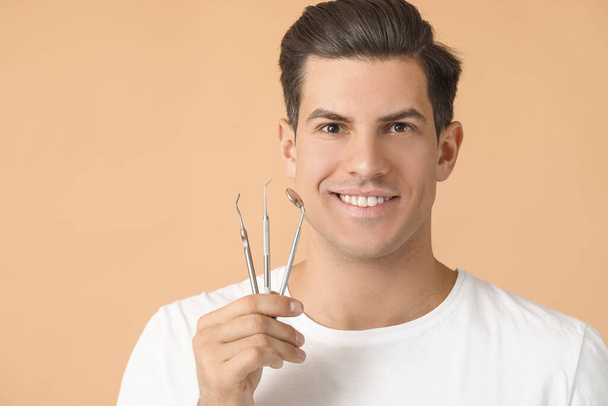 Young man with dental tools on color background - Photo, Image