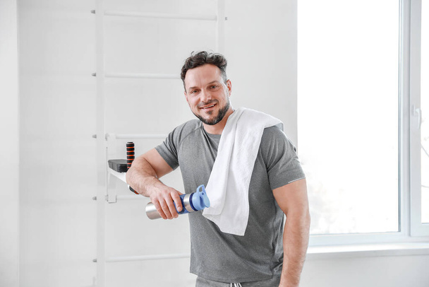 Sporty man with bottle of water in gym - Photo, Image