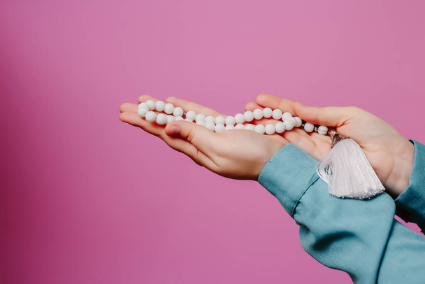 Muslim rosary in hands. On a pink background - Fotografie, Obrázek